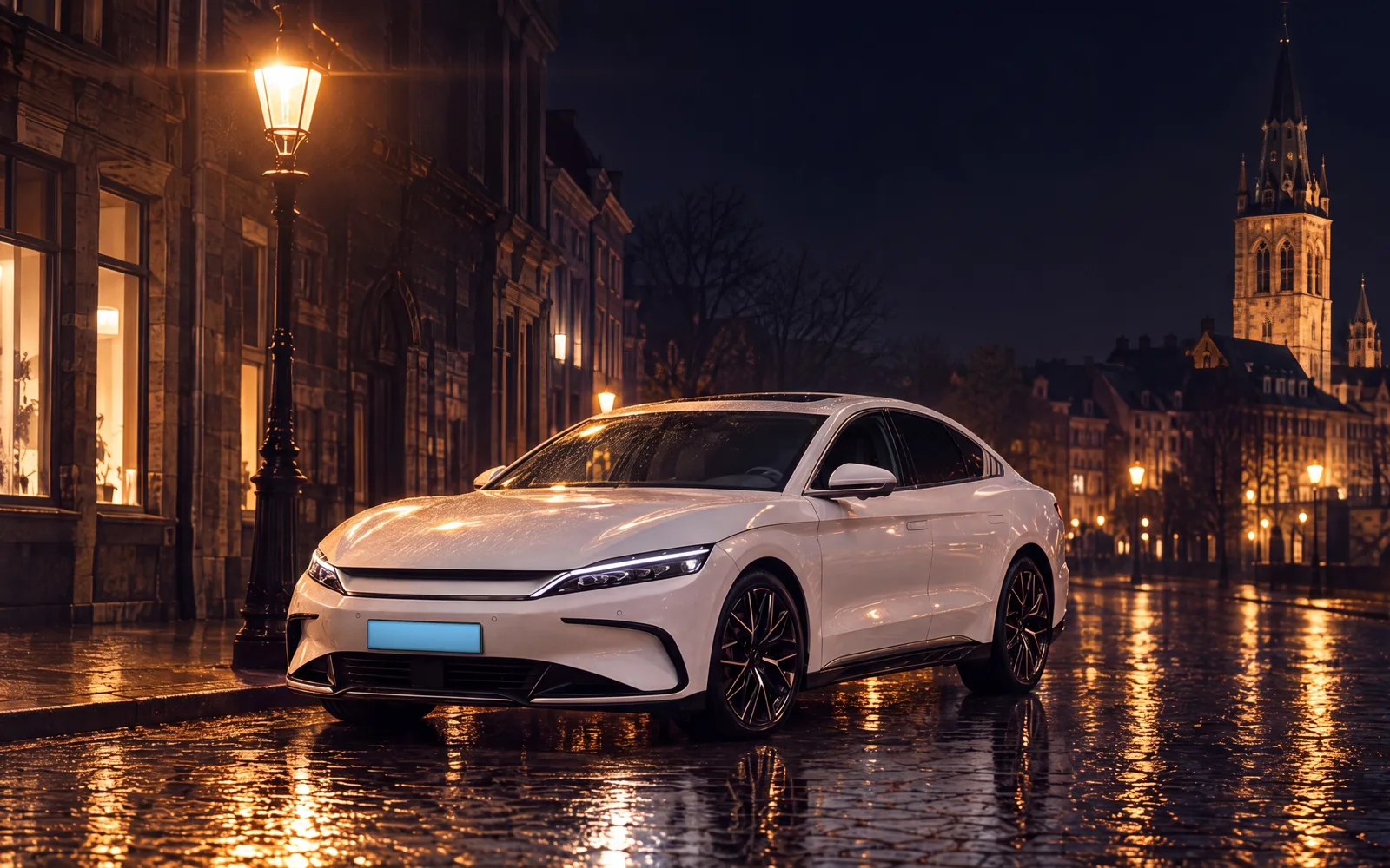 Witte elektrische sedan geparkeerd in een verlichte historische straat bij nacht, kerktoren op de achtergrond